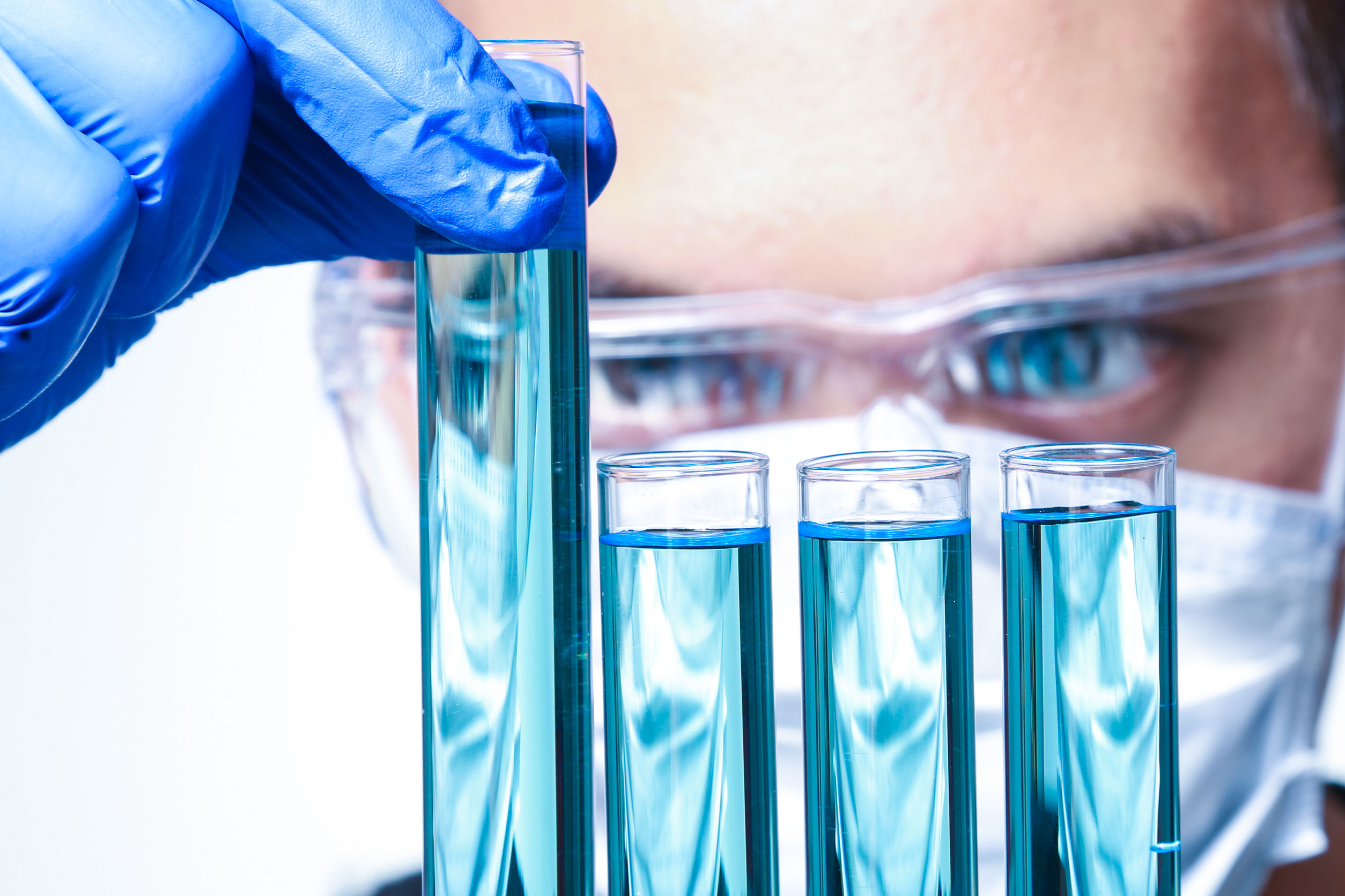 Scientist working in a lab looking at test tubes full of a blue substance
